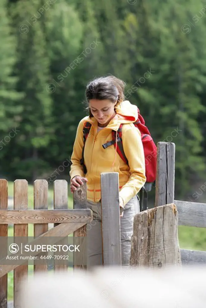 Woman passing a fence door, Heiligenblut, Hohe Tauern National Park, Carinthia, Austria