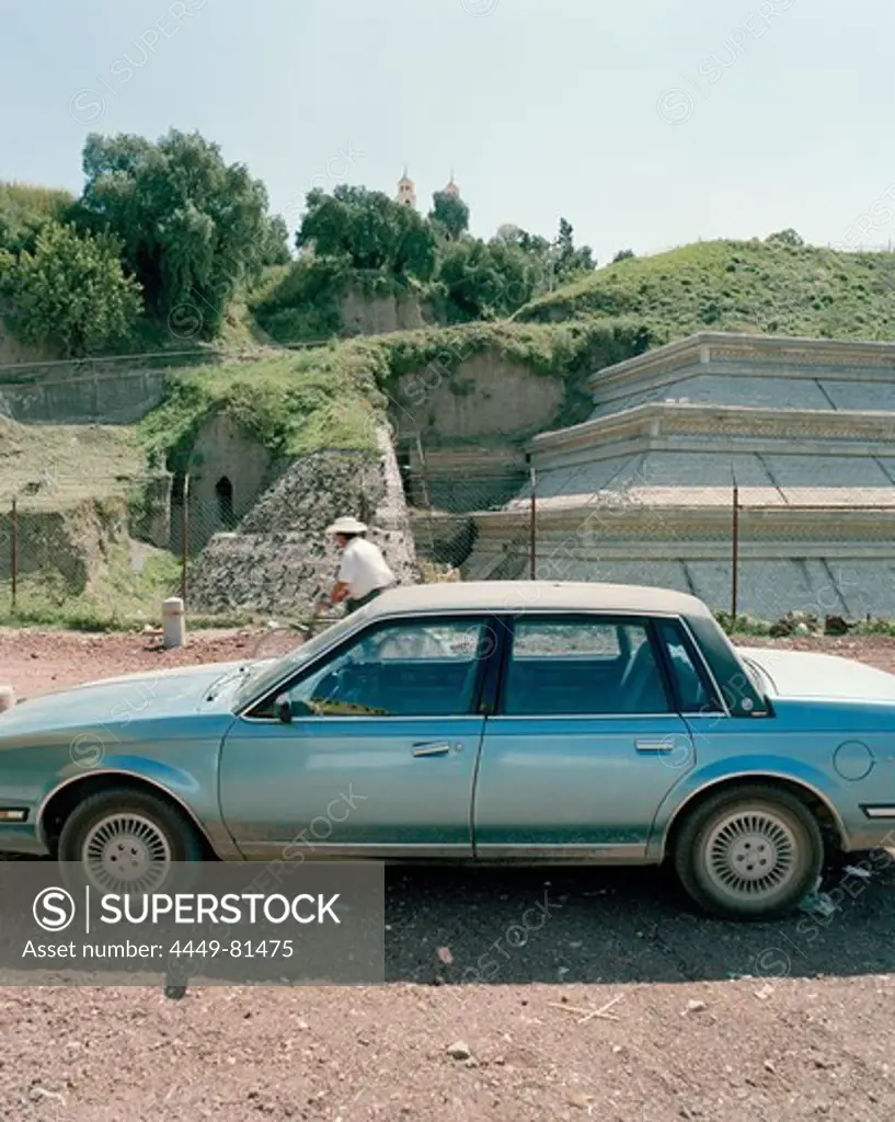 Parking car in front of overgrown Aztec pyramid, Cholula, Puebla province, Mexico, America