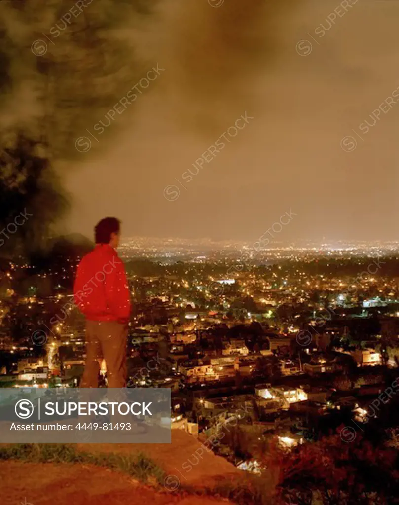 A man looking from Barrio Xochimilco at the lights of Mexico City, Mexico, America