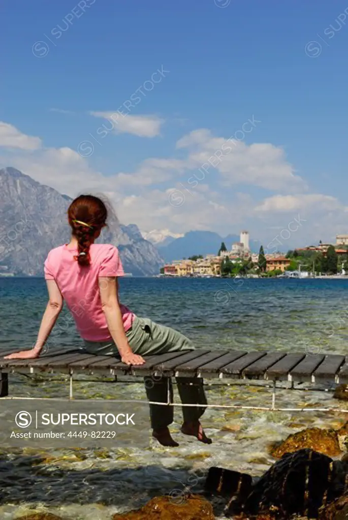 Woman sitting on landing stage at lake Garda, Malcesine, Veneto, Italy