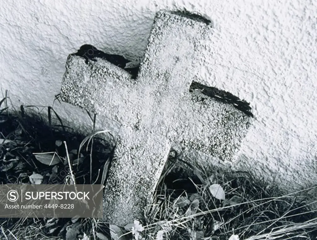 A cross made of stone leaning on a wall