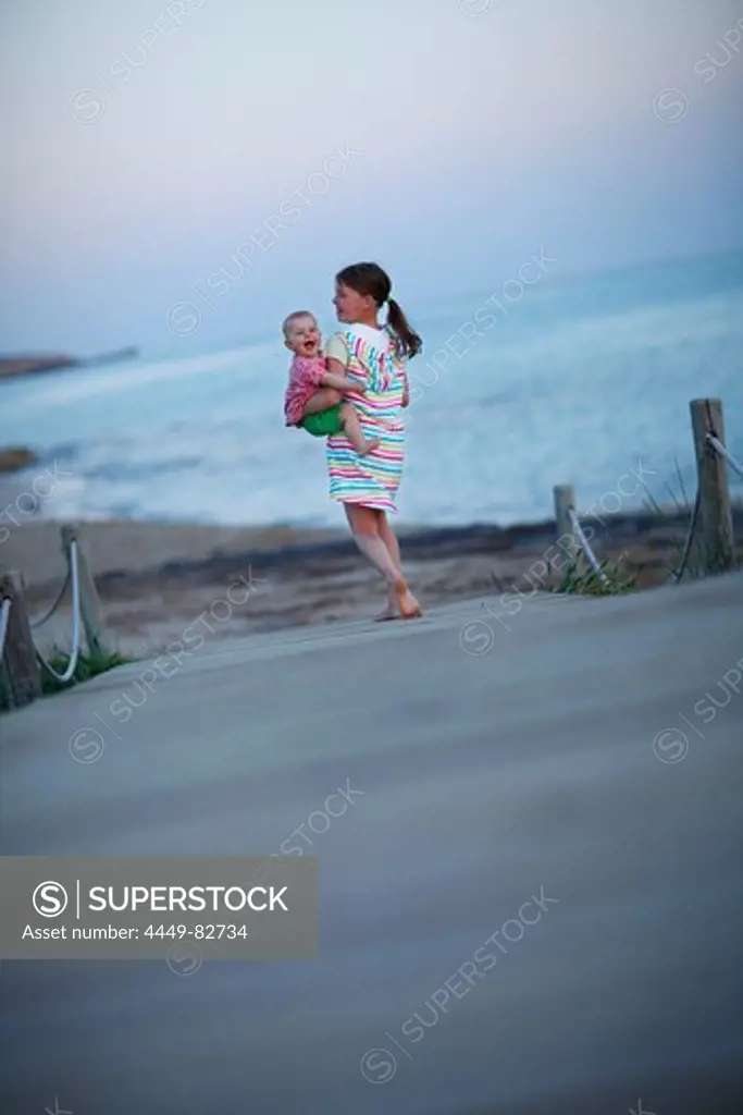 Girl carrying baby on jetty, Formentera, Balearic Islands, Spain