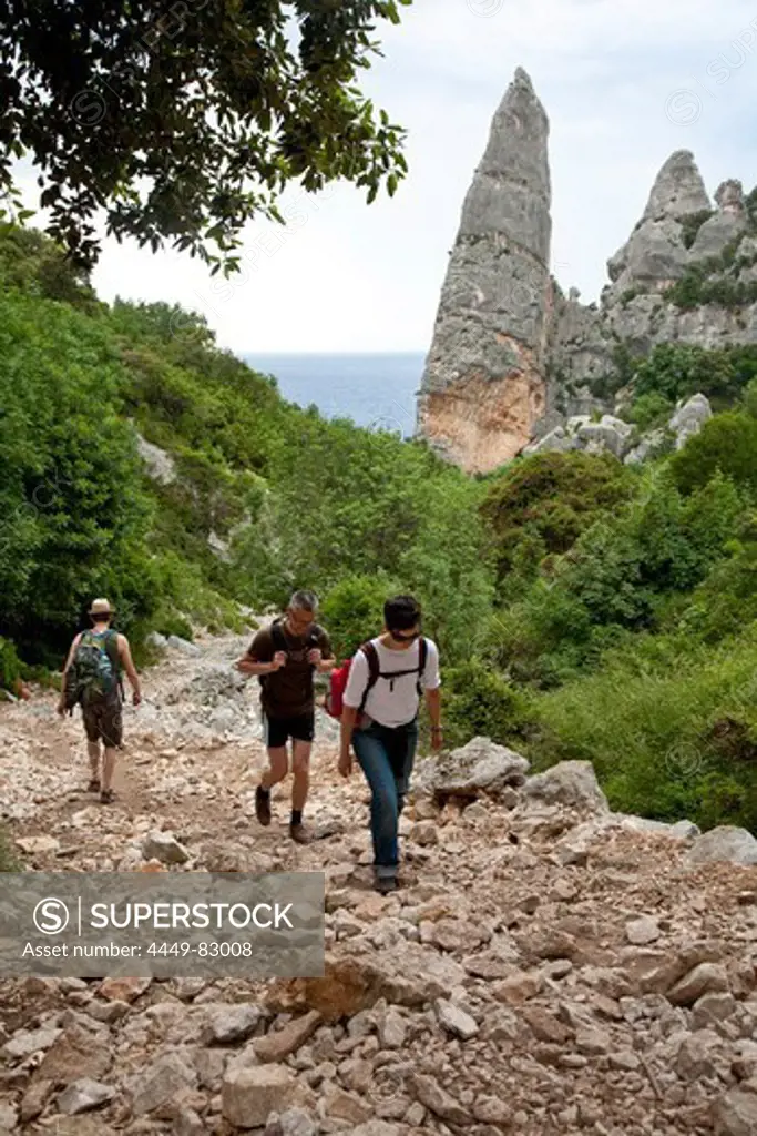 Three hikers on a stony hiking trail, Punta Goloritzé, Golfo di Orosei, Sardinia, Italy, Europe