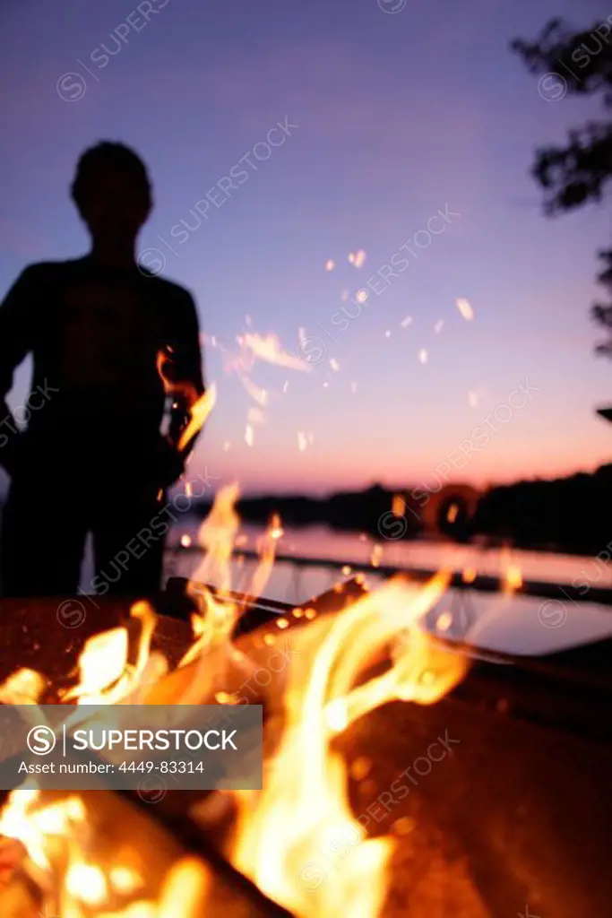 Fireplace, man in background, lake Worthsee, Bavaria, Germany
