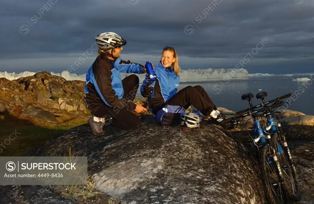 A couple having a break after mountainbiking, Jakobshavn, Ilulissat, Greenland