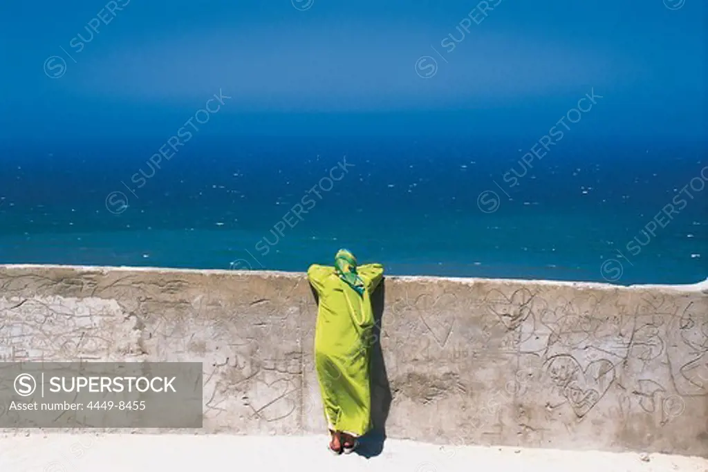 Woman leaning on a wall looking at the sea, Medina, Tanger, Morocco, Africa