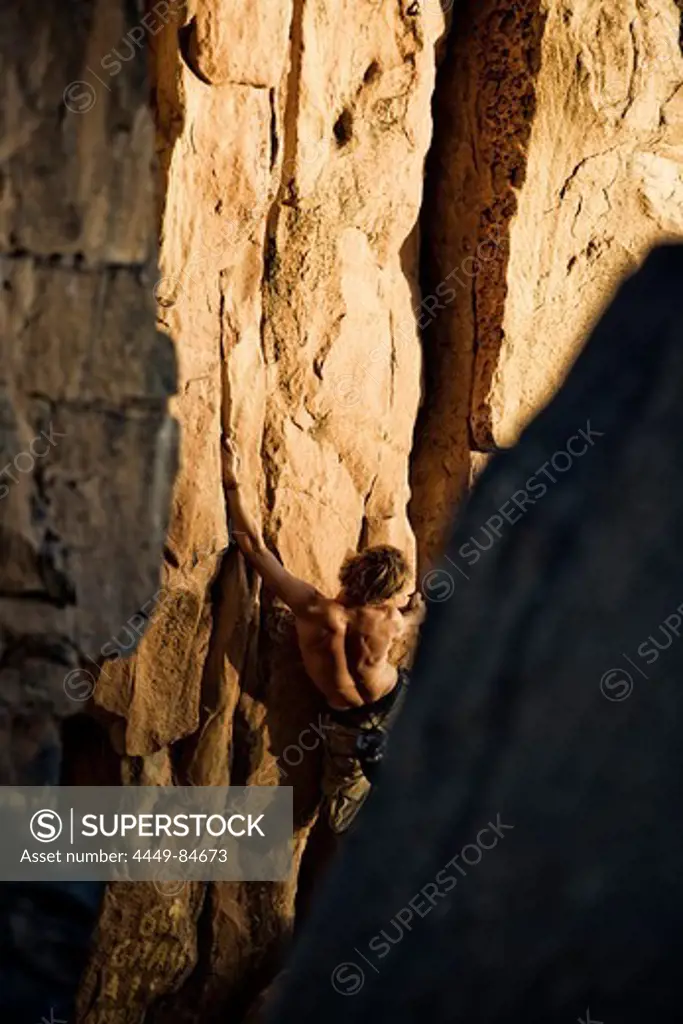 Young man bouldering in the evening sun, Hand of Fatima, Hombori, Mali, Africa