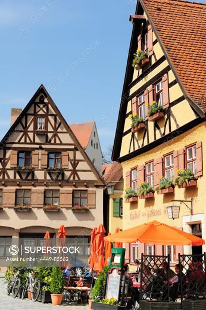 Guests sitting in the beer garden of a restaurant, half-timbered houses, Dinkelbuehl, Bavaria, Germany