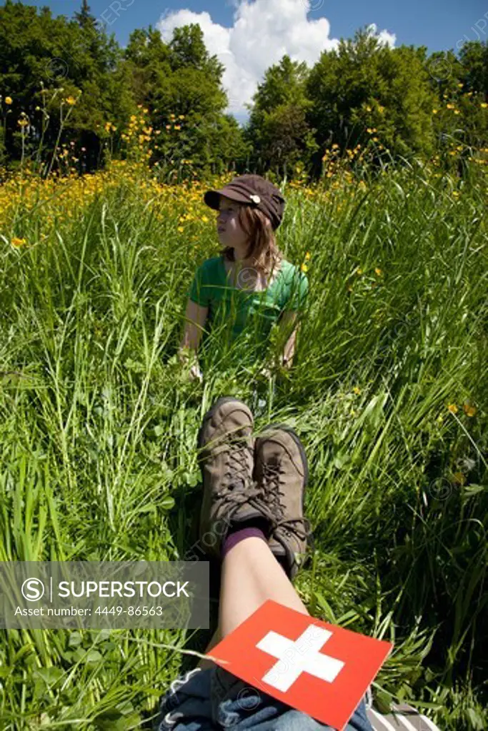 Girl and adult resting in meadow at mount Niesen, Bernese Oberland, Canton of Bern, Switzerland