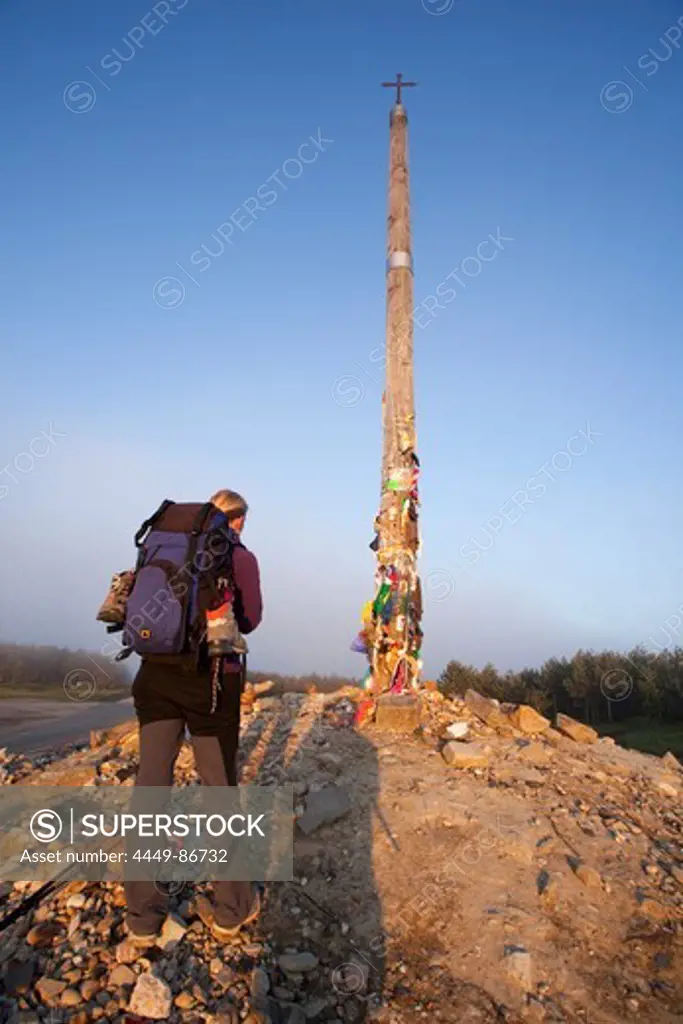 Pilgrim at iron cross, Cruz del Ferro, Province of Leon, Old Castile, Castile-Leon, Castilla y Leon, Northern Spain, Spain, Europe