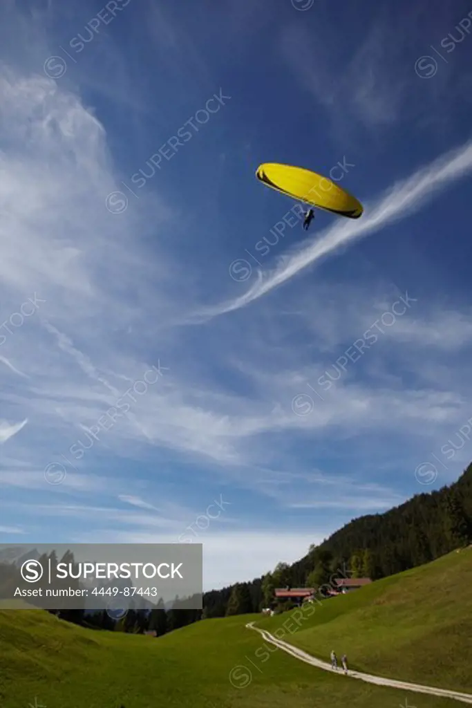 Paraglider landing on alpine meadow at Gschwandtnerbauer, Garmisch-Partenkirchen, Bavaria, Germany, Europe