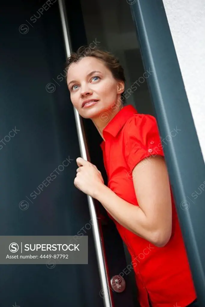 Young woman looking out of a door