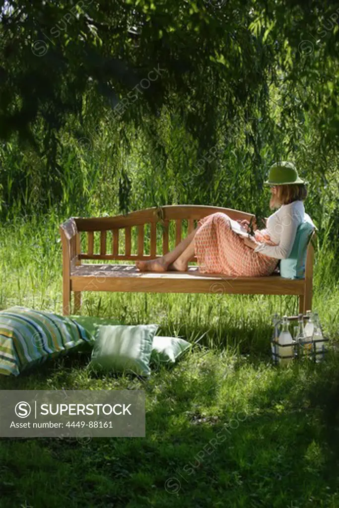 Woman sitting on a garden bench, Simssee, Bavaria, Germany