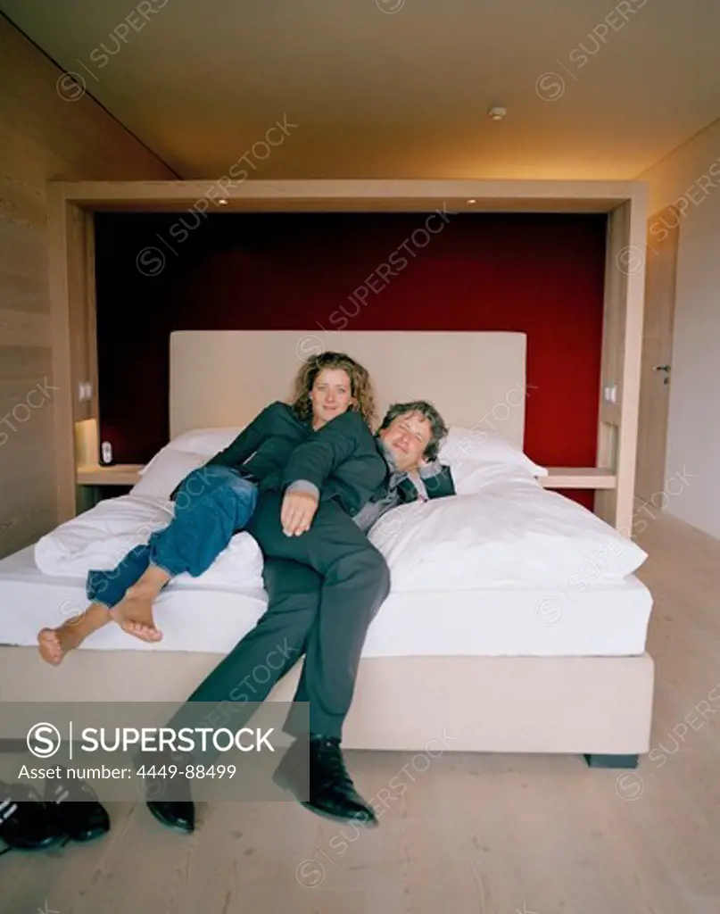 Couple on a bed in a hotel room, Vigilius Mountain Resort, Vigiljoch, Lana, Trentino-Alto Adige/Suedtirol, Italy
