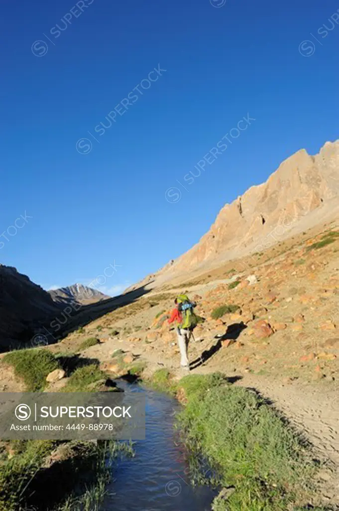 Woman hiking along a stream, Sirsir La, between Honupatta and Photoksar, Zanskar Range Traverse, Zanskar Range, Zanskar, Ladakh, Jammu and Kashmir, India