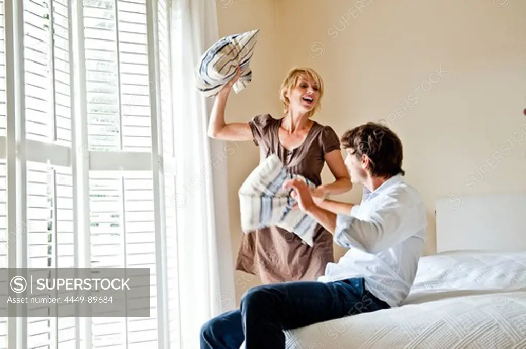 Young couple at a pillow-fight in a bedroom, Hamburg, Germany
