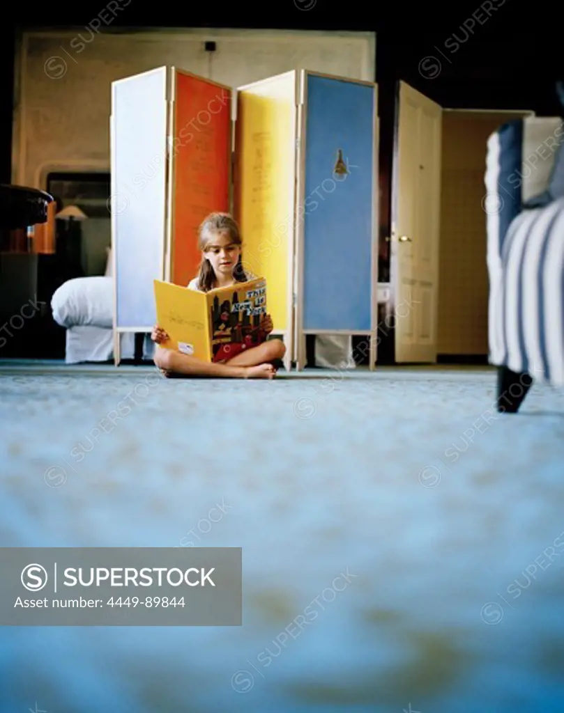 Girl reading on the floor inside a hotel room, Rotterdam, Netherlands