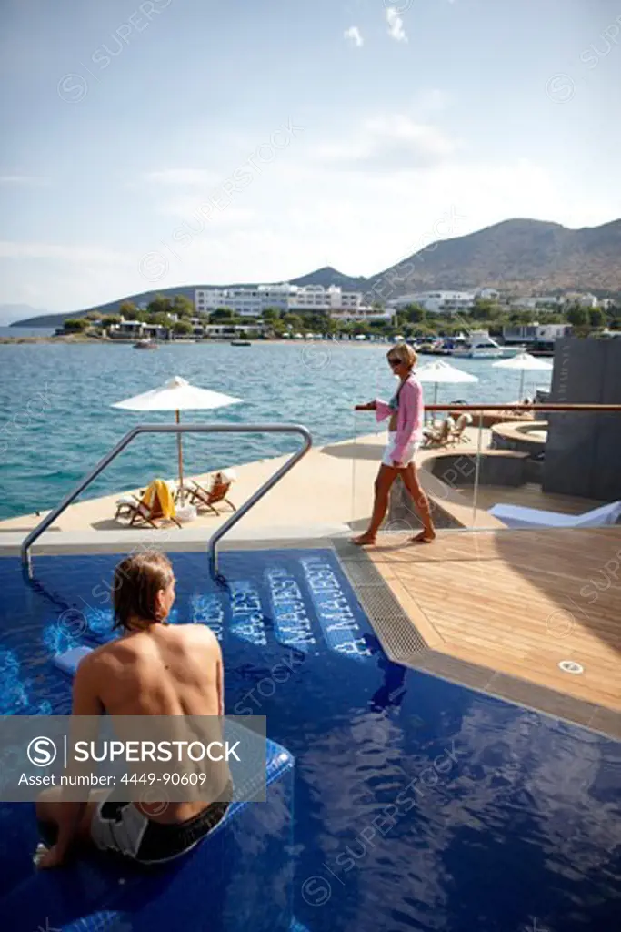 Man and woman at the pool and on the deck of the Yachting Club Villas, Elounda Beach Resort, Elounda, Crete, Greece