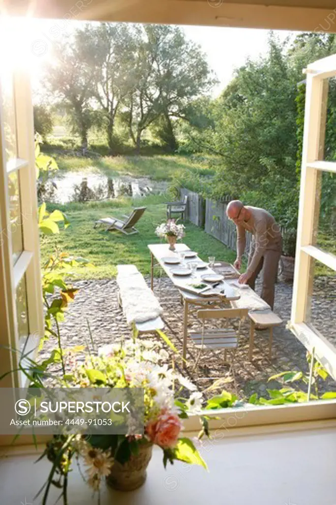 Man setting a table in a garden, Klein Thurow, Roggendorf, Mecklenburg-Western Pomerania, Germany