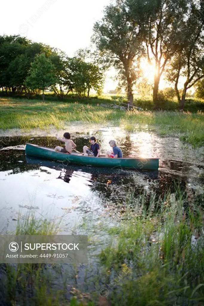 Three boys in a canoe on a pond, Klein Thurow, Roggendorf, Mecklenburg-Western Pomerania, Germany