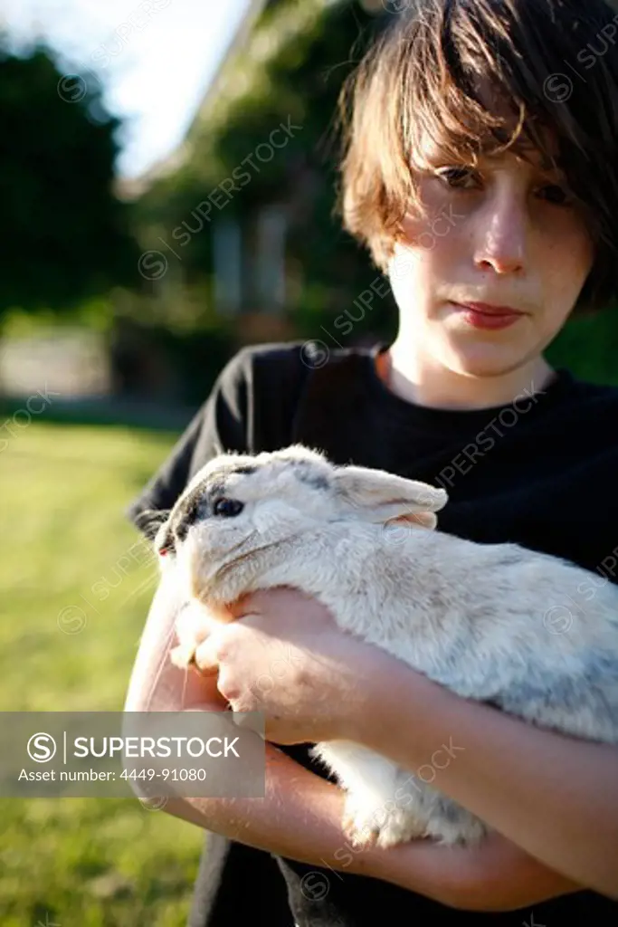 Boy holding rabbit in his arms, Klein Thurow, Roggendorf, Mecklenburg-Western Pomerania, Germany