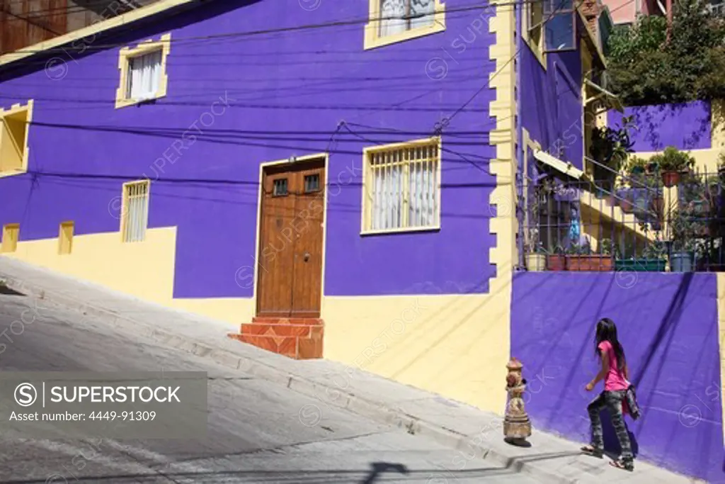 Girl walks up steep street past purple building, Valparaiso, Valparaiso, Chile, South America
