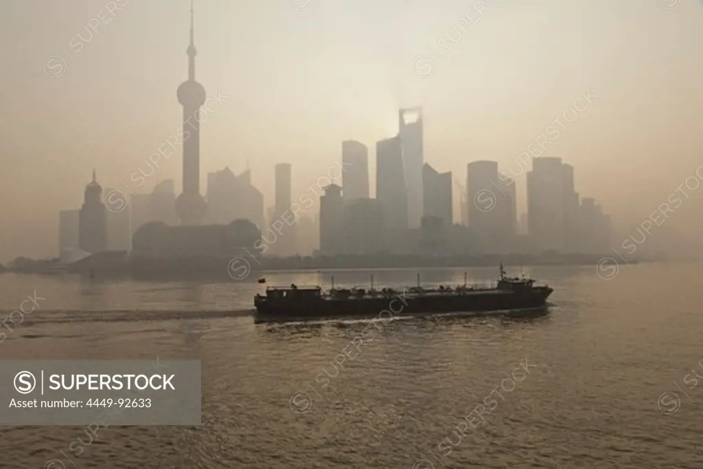 Skyline of Pudong and freighter on Huangpu River at dawn, Pudong, Shanghai, China, Asia