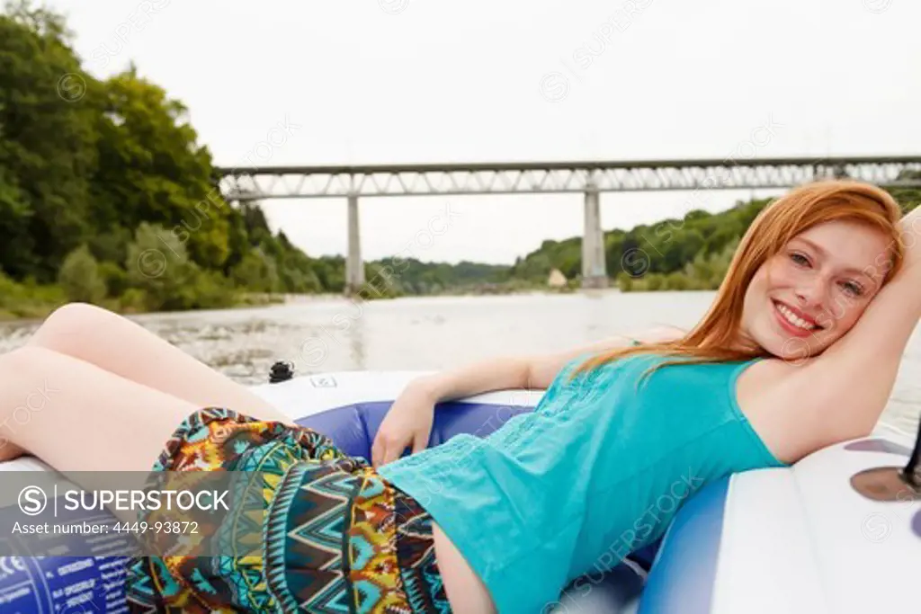 Young woman lying in a rubber dinghy at Isar river, Munich, Bavaria, Germany
