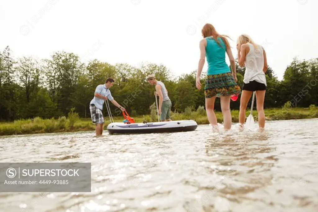 Young people with a rubber dinghy at the Isar river, Munich, Bavaria, Germany