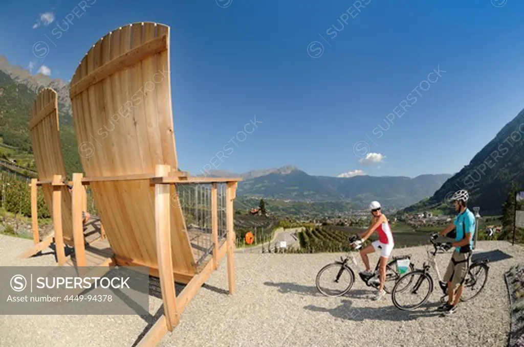 Giant chairs, view from Algund towards Meran, Couple on electric bikes, E-bikes, South Tyrol, Italy