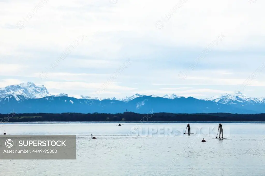Stand-up-Paddlers on Lake Starnberg in April, overlooking Alps and Zugspitze, Fuenfseenland, Wettersteingebirge, Bavarian Alps, Upper Bavaria, Germany
