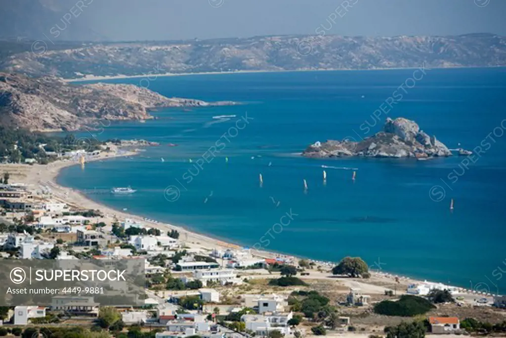 View over beach and bay of Kefalos with surfer to Kastri island with chapel St. Nicholas, Kefalos, Kos, Greece