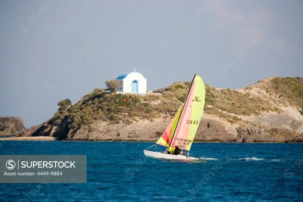 Catamaran passing Kastri island with capel St. Nicholas, Kefalos, Kos, Greece