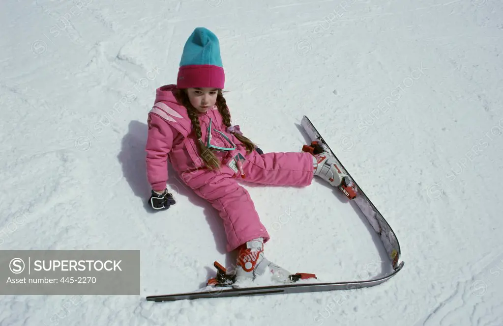 Young girl sitting with skis on the snow