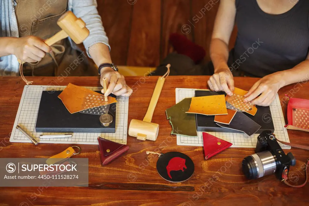 High angle view of two women sitting at a table, working in a leather shop.