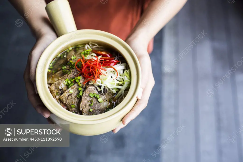 High angle close up of person holding bowl of Bun Bo Hue.