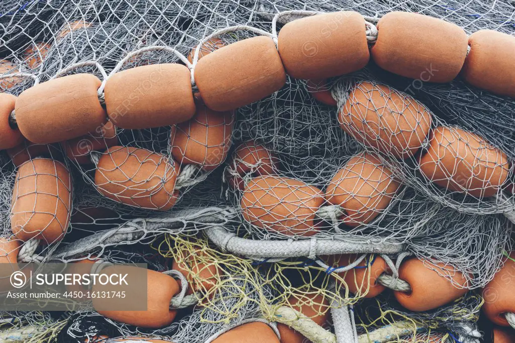 Pile of commercial fishing nets and gill nets on a fishing quay. -  SuperStock