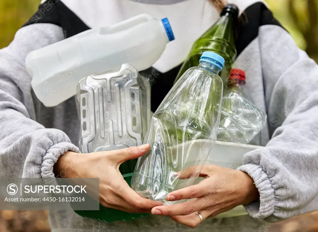 Woman holding armful of used plastic packaging and bottles