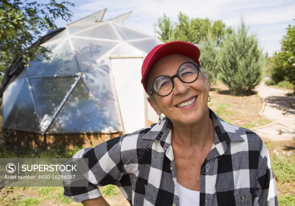 senior woman gardening in geodesic dome, Santa Fe, NM.