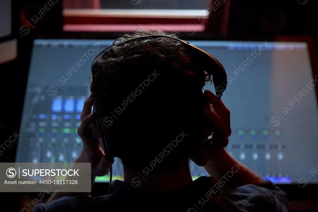 Man working in music studio, using large computer screen