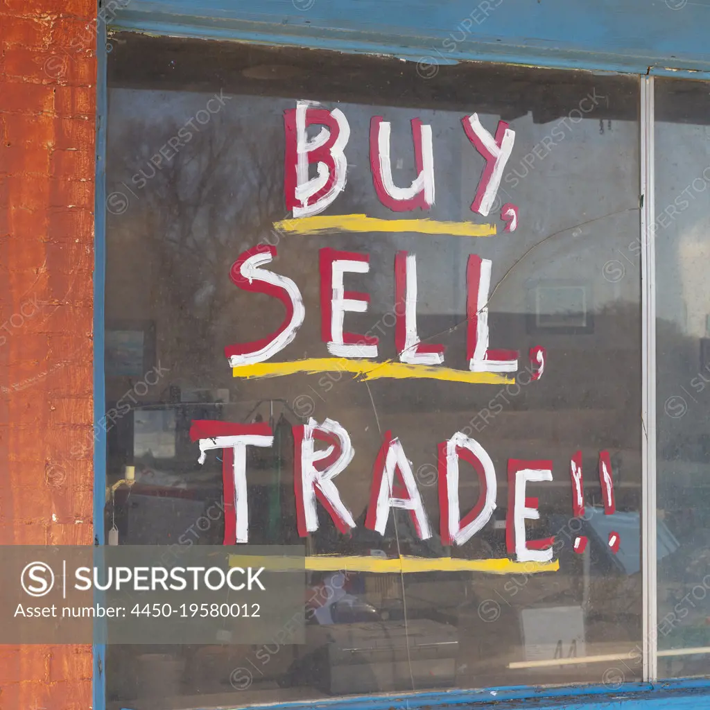 Buy Sell Trade sign in on old storefront window.