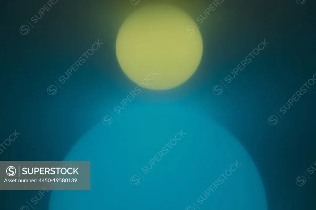 Illuminated spherical orbs, one large blue one and one small yellow one. 
