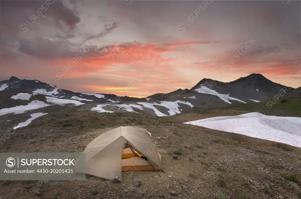 A small tent pitched on a screen slope just below the snowline, at sunset in the Mount Baker wilderness. 
