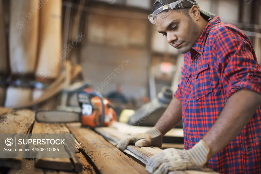 A reclaimed lumber workshop. A man measuring and checking planks of wood for re-use and recycling. Woodstock, New York, USA