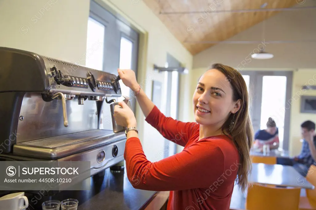 A young woman making coffee using a large coffee machine. Stone Ridge, New York, USA