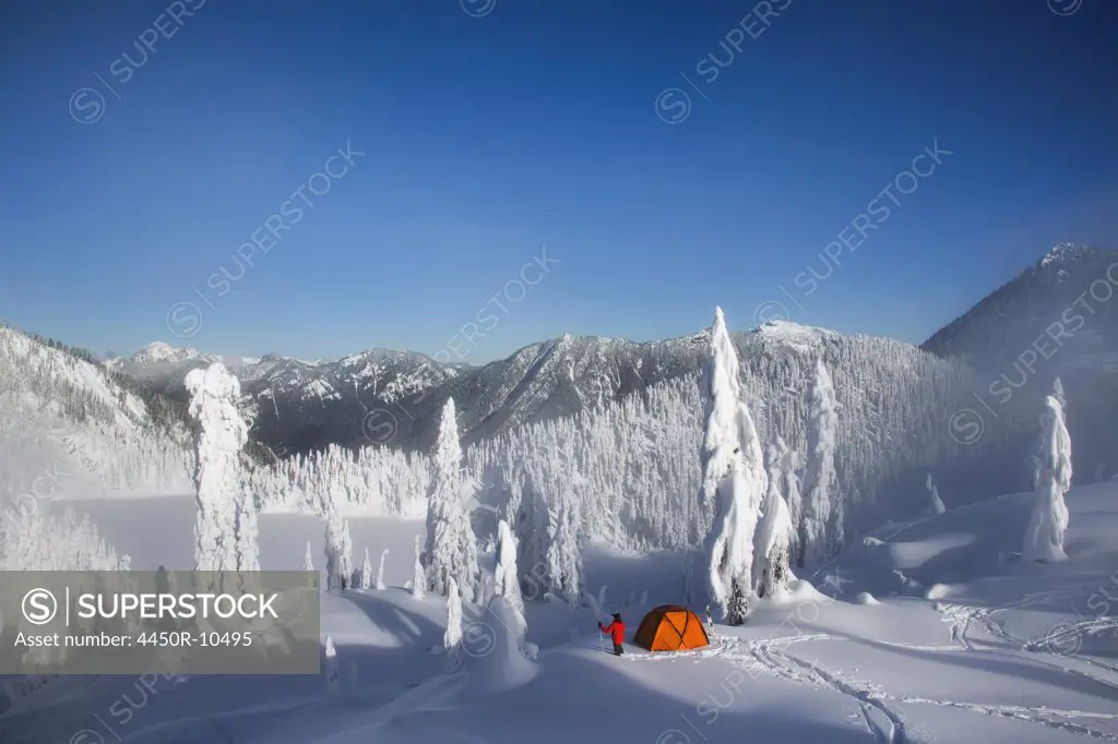 Michael Hanson walks through deep powder to his campsite in the snow covered Cascade Mountains overlooking Snow Lake.Cascade Mountains, Washington, USA