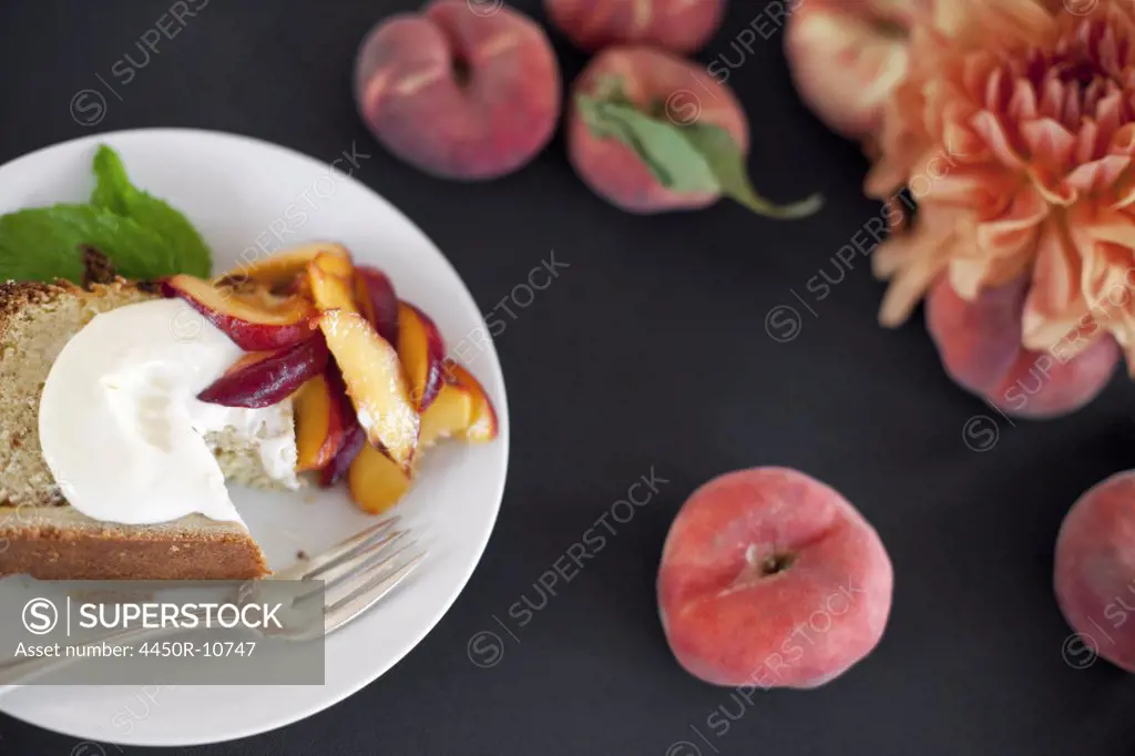 A table viewed from overhead. Organic fruit, peaches, and flowers. a plate with fresh fruit, cake and creme fraiche. A fork. Dessert. Park City, Utah, USA