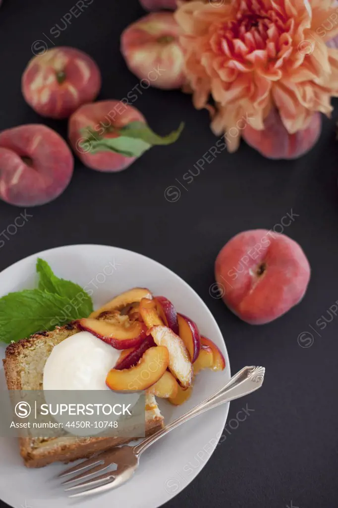A table viewed from overhead. Organic fruit, peaches, and flowers. a plate with fresh fruit, cake and creme fraiche. A fork. Dessert. Park City, Utah, USA