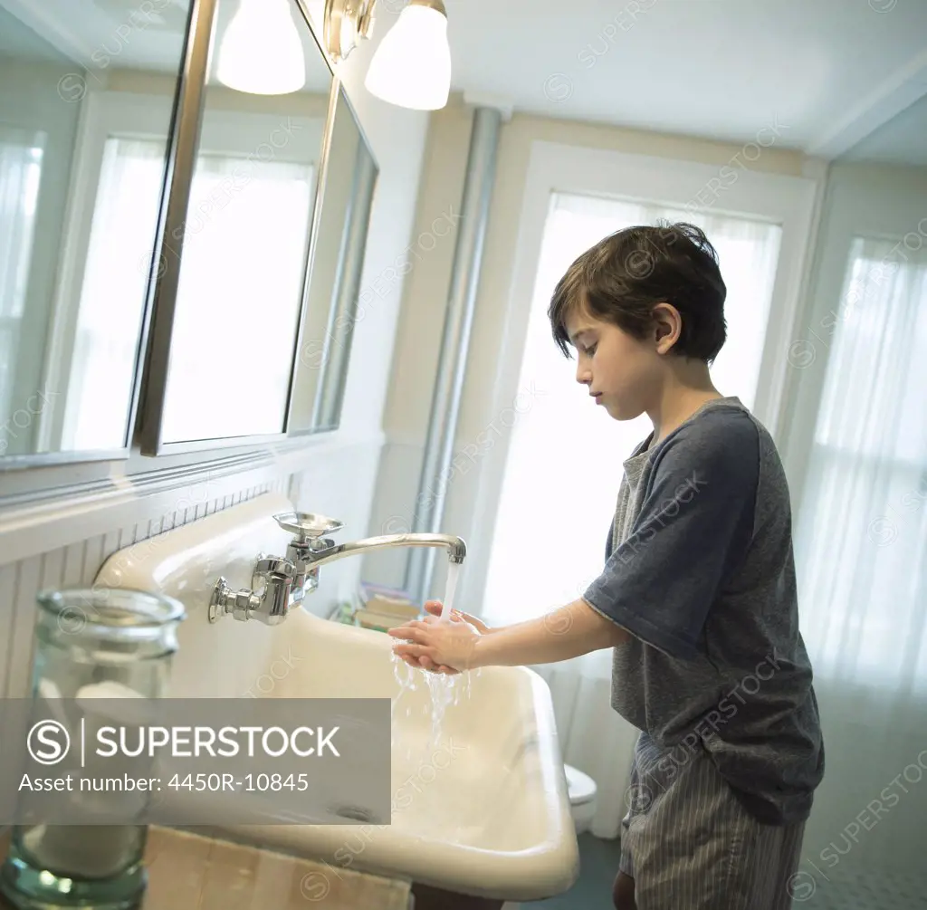 A boy standing in the bathroom, washing his hands under the tap. Woodstock, New York, USA