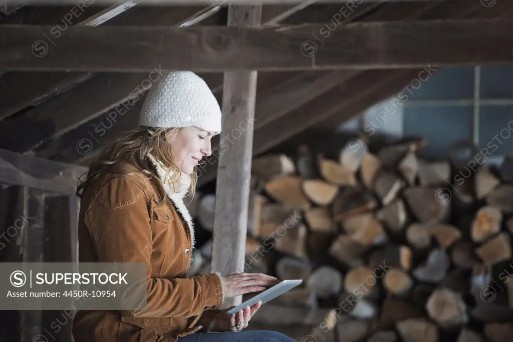 An organic farm in upstate New York, in winter. A woman sitting in an outbuilding using a digital tablet.  West Kill, New York, USA